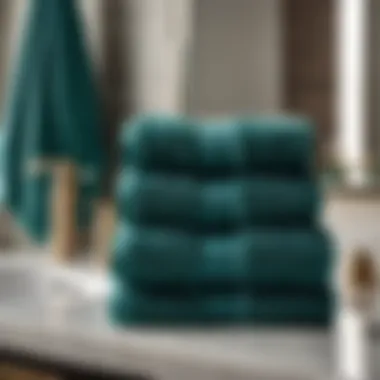 A stack of neatly folded dark turquoise bath towels on a marble countertop