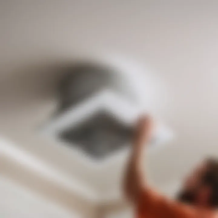 Person installing new bathroom exhaust fan in the ceiling